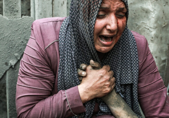 A wounded woman cries as she holds the hand of her dead relative outside her home following Israeli airstrikes in Gaza City, Oct. 23, 2023. Photo: Abed Khaled/AP.