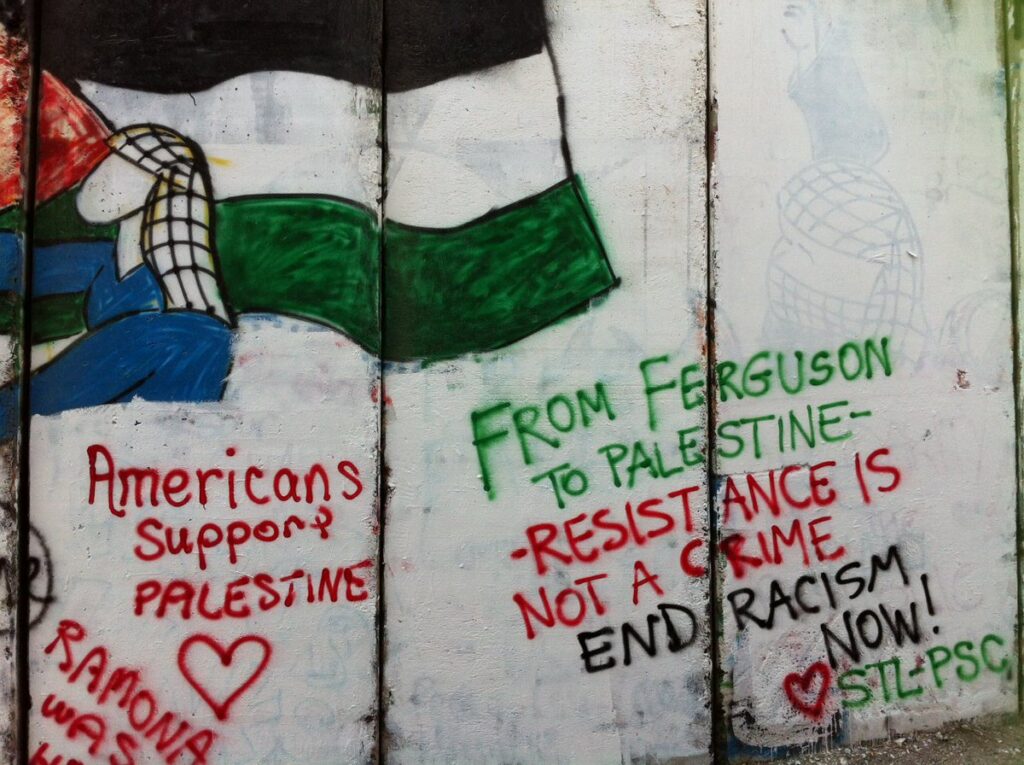 A mural on a wall depicting a person holding a Palestinian flag (left) and the following caption (right): “From Ferguson to Palestine, Resistance is not a crime, end racism now!” Photo: Sotwe.com/File photo.