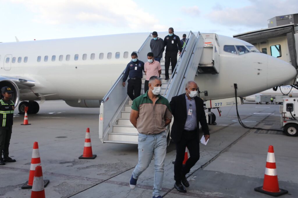 Three Venezuelans, recently repatriated from the United States, exiting the plane that brought them to Venezuela, handcuffed and escorted by law enforcement agents. Photo: X/@CeballosIchaso1.