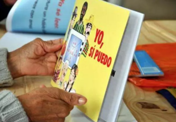 A person holding a literacy program book that says in Spanish "Yo, si puedo" and in English means "Yes, I can." Photo: Prensa Latina/File photo.