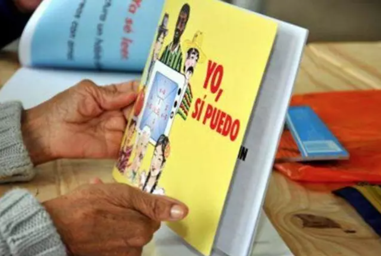A person holding a literacy program book that says in Spanish "Yo, si puedo" and in English means "Yes, I can." Photo: Prensa Latina/File photo.