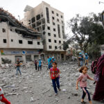 Residents move away for safer spots amid destroyed buildings and debris around the Palestinian Telecommunications Company, which was targeted, after Israeli airstrikes in Gaza Strip on October 10, 2023. Photo: Anadolu Agency.