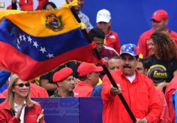 Venezuelan President Nicolás Maduro flies the national flag, accompanied by supporters. File photo.