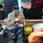 A migrant father from Venezuela feeds his 15-month-old son in the lobby of a police station where their family has been staying since their arrival to Chicago on May 9, 2023. Photo: Scott Olson/Getty