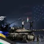Photo composition showing two men over Israeli tanks waving the Palestinian flag, with the Ukrainian and the Palestinian flags to the right and the US flag watermarked in the upper right corner. Photo: Al-Mayadeen.