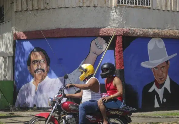 A motorcyclist rides past a mural of Nicaraguan President Daniel Ortega (left) and revolutionary hero César Augusto Sandino (right). Photo: Andres Nunes/AP.