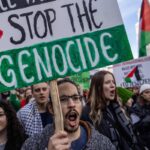 A demonstrator displays a placard with the lettering reading 'Stop the Genocide' during a rally in solidarity with the Palestinians in the Gaza Strip at Warsaw, Poland on October 29, 2023.  Photo by Wojtek Radwanski/AFP.
