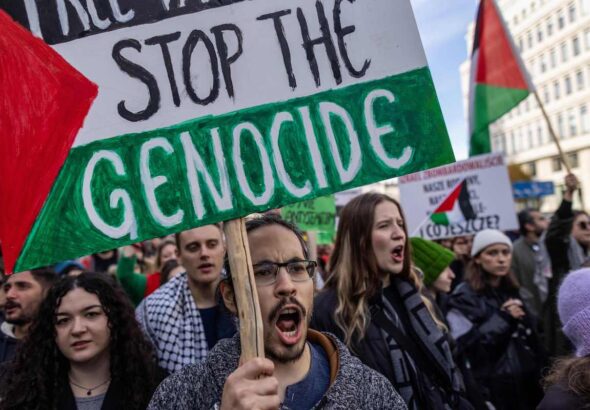 A demonstrator displays a placard with the lettering reading 'Stop the Genocide' during a rally in solidarity with the Palestinians in the Gaza Strip at Warsaw, Poland on October 29, 2023.  Photo by Wojtek Radwanski/AFP.