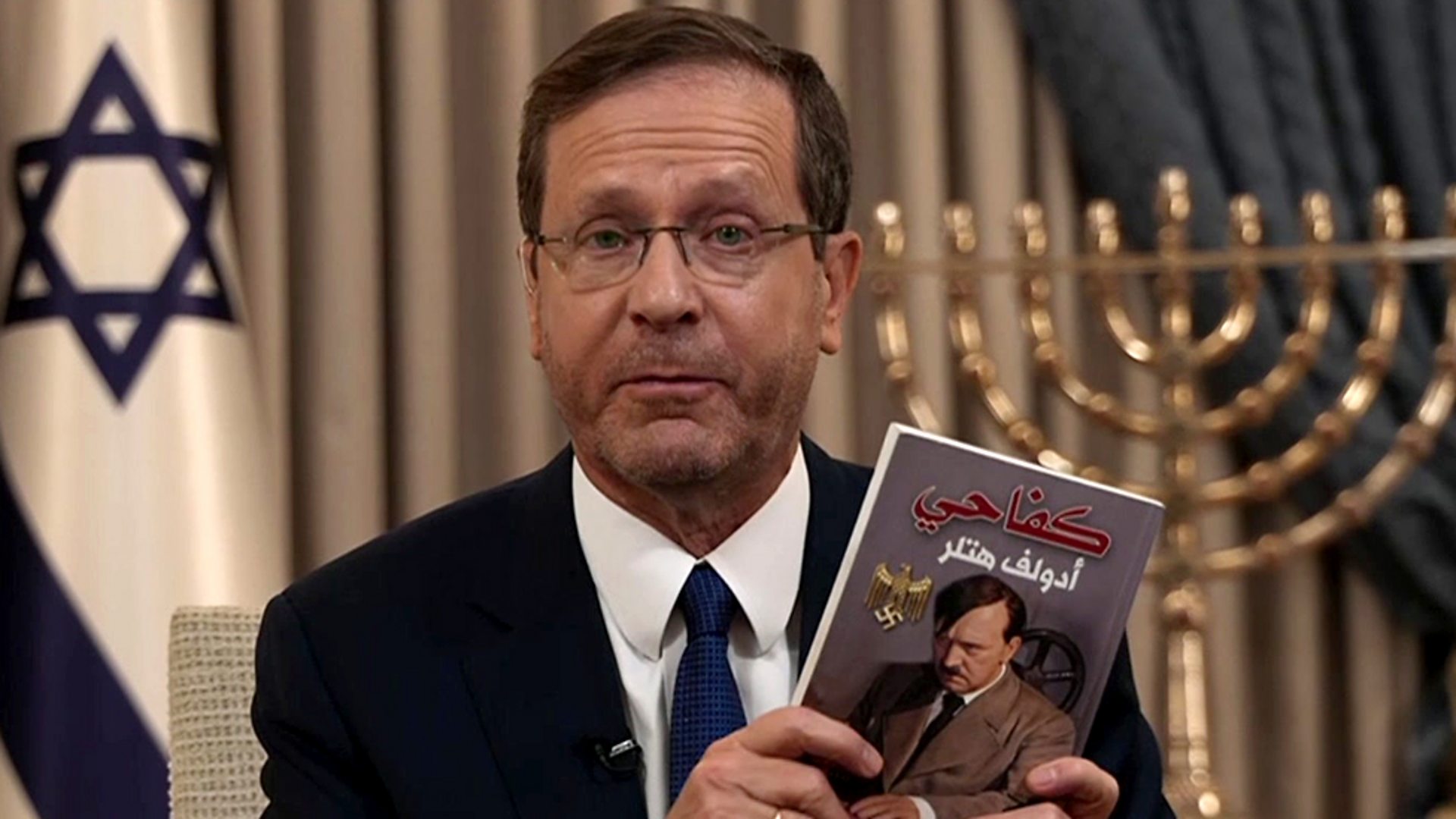 The president of the Israeli settler entity, Isaac Herzog, showing a copy of Hitler’s Main Kampf book in Arabic allegedly found in a raided house, in a pathetic attempt to justify the genocide his government is conducting against Palestinians in Gaza. Photo: BBC/File photo.