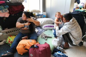 A migrant couple from Venezuela and their 15-month-old son stay in the lobby of a police station in Chicago on May 9, 2023. Photo: Scott Olson/Getty Images.