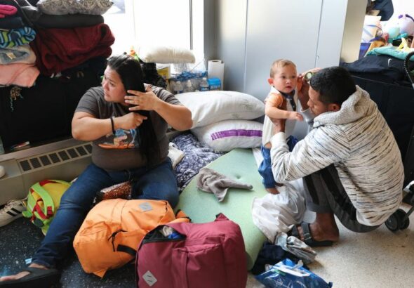 A migrant couple from Venezuela and their 15-month-old son stay in the lobby of a police station in Chicago on May 9, 2023. Photo: Scott Olson/Getty Images.