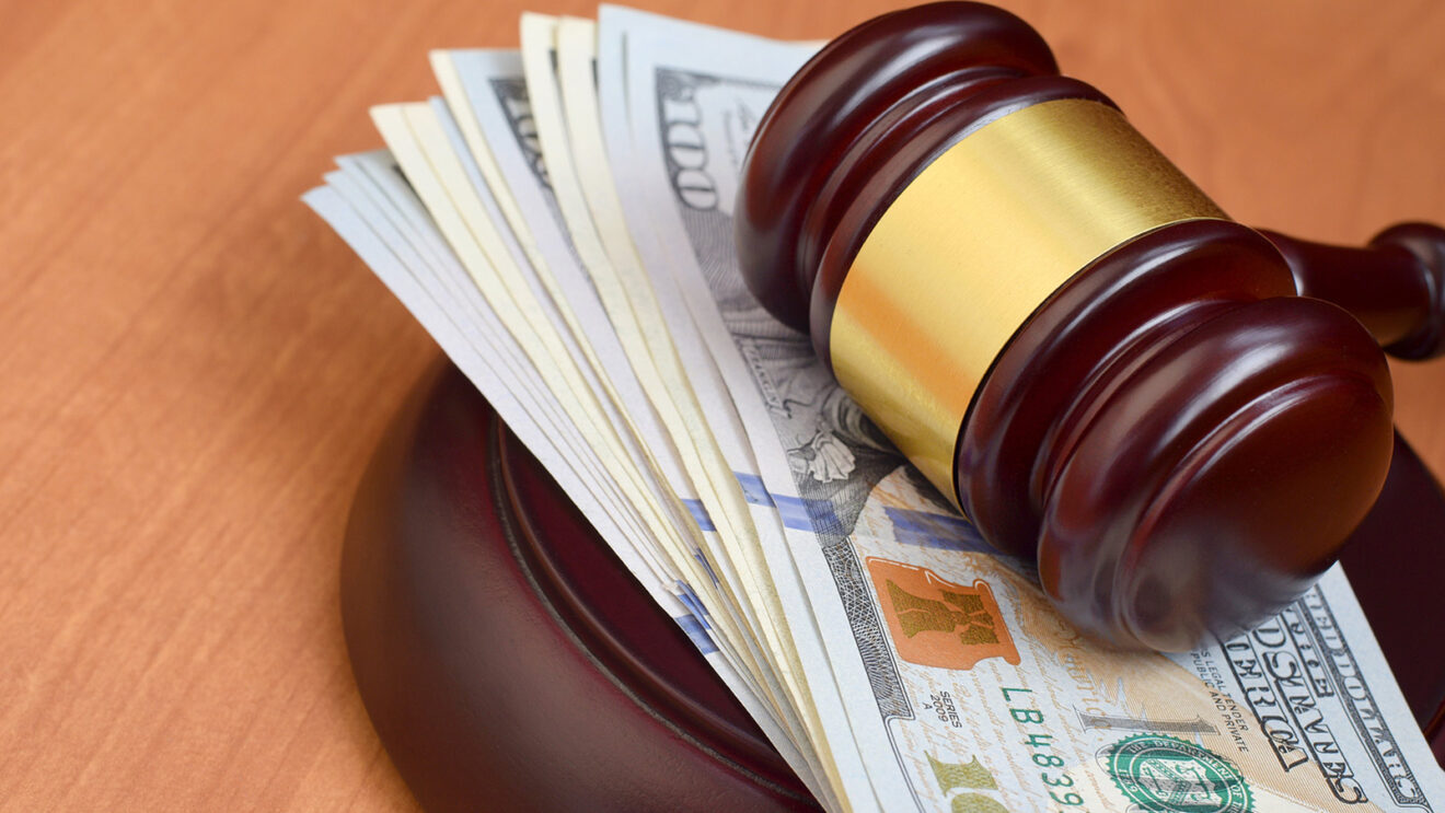 Judge's gavel laying on a pack of $100 bills. Photo: File photo.