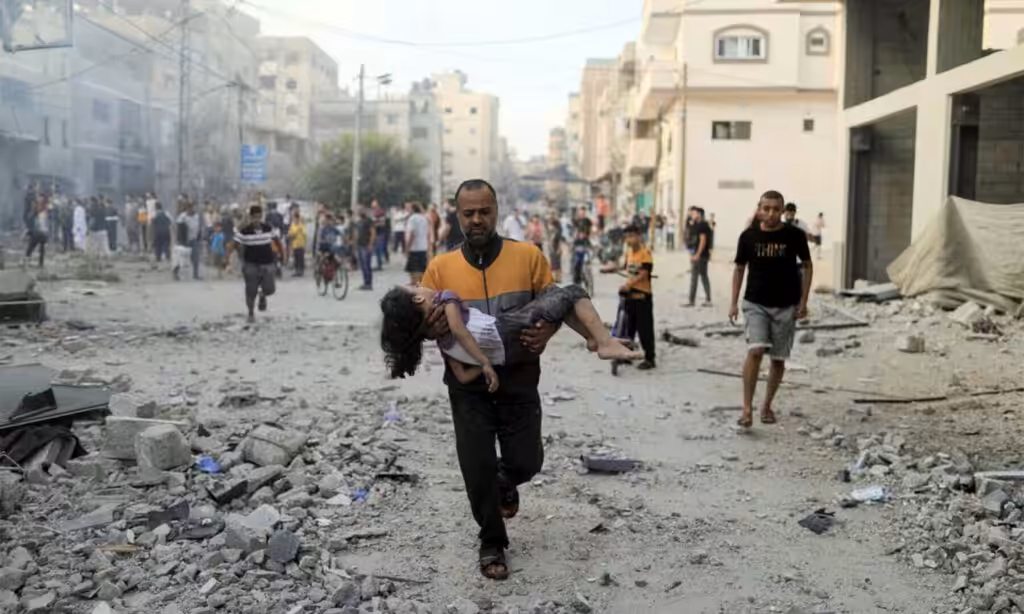 Calling Israel’s bombing of Palestinian civilians an act of ‘self-defence’ is a disingenuous labelling of Israel’s actions: a Palestinian man carries a wounded girl at the site of Israeli strikes, in Khan Younis in the southern Gaza Strip, October 14, 2023. Photo: Reuters.