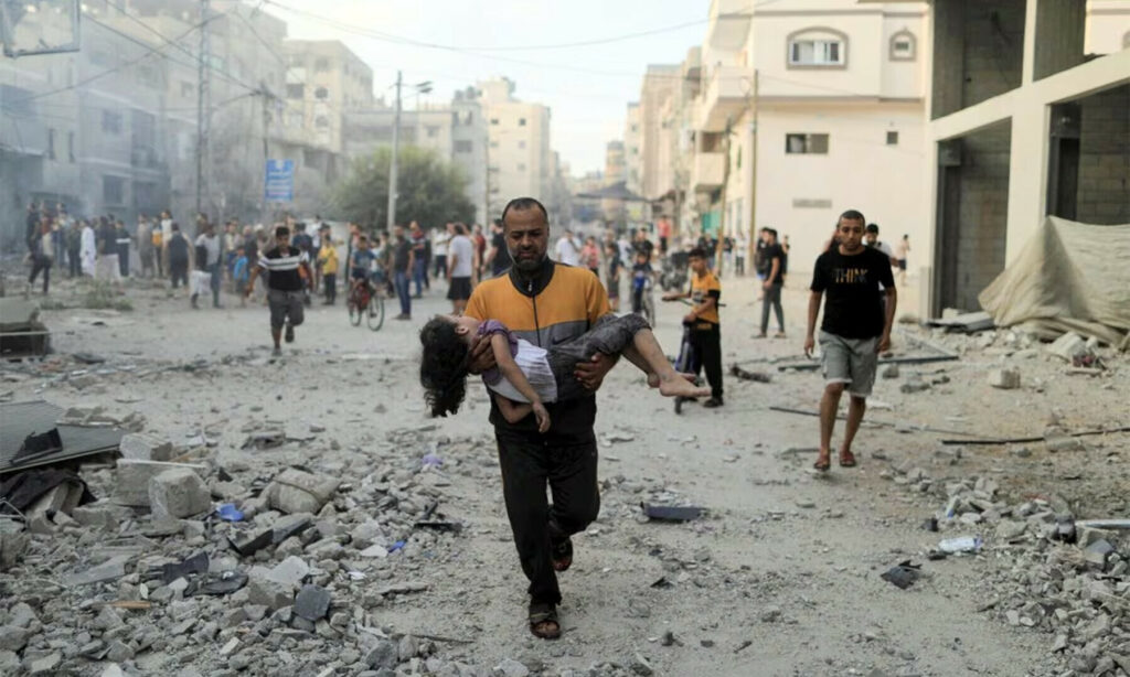 Calling Israel’s bombing of Palestinian civilians an act of ‘self-defence’ is a disingenuous labelling of Israel’s actions: a Palestinian man carries a wounded girl at the site of Israeli strikes, in Khan Younis in the southern Gaza Strip, October 14, 2023. Photo: Reuters.