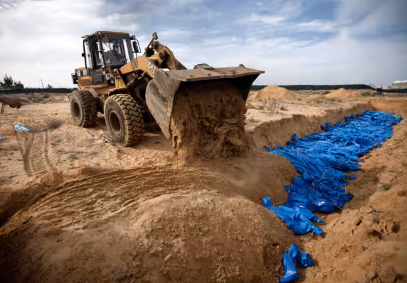 Palestinians bury innocent civilians killed by the Israeli entity's genocidal bombardment in a mass grave in the town of Khan Younis, southern Gaza Strip, Wednesday, Nov. 22, 2023. Photo: Mohammed Dahman/AP.