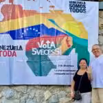 Orinoco Tribune editor, Jesus Rodriguez-Espinoza, and his wife Yullma Hernandez next to a banner for the Essequibo Referendum campaign showing the map of Venezuela (including the Essequibo territory) and the following caption: "Venezuela is all of us, all Venezuela vote 5 times yes. On December 3, we have an appointment with the homeland, Venezuela is calling us!" Photo: Orinoco Tribune.