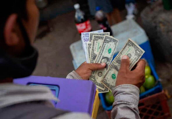 Street vendor counting US dollars along with bolívars. File photo.