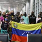 Venezuelan migrants returning to their country through the government's Vuelta a la Patria program pose with the flag of Venezuela. File photo.