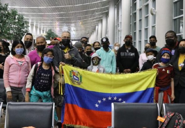 Venezuelan migrants returning to their country through the government's Vuelta a la Patria program pose with the flag of Venezuela. File photo.