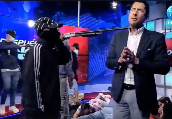 An Ecuadorian news anchor for TC Channel making statements with a shotgun against his neck, while a criminal gang took control of the broadcast live on camera. Photo: TC Channel/The Economist.