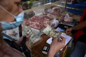 A customer pays for her purchase with US dollar banknotes in an open-air fruit and vegetable market in Caracas, Venezuela February 10, 2023. Photo: Gaby Oraa/Reuters.
