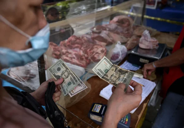A customer pays for her purchase with US dollars in an open-air fruit and vegetable market in Caracas, Venezuela, on February 10, 2023. Photo: Gaby Oraa/Reuters.