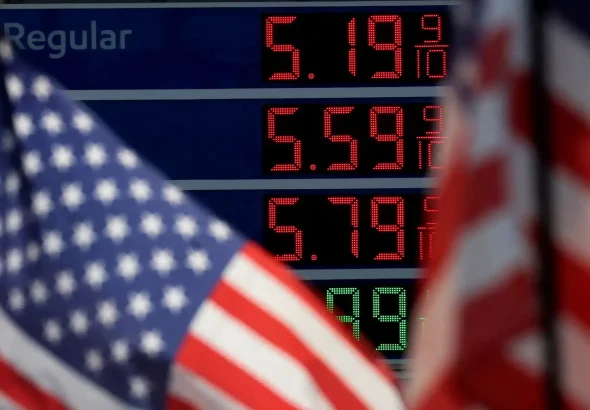 Prices of gas at a US gas station next to US flags. Photo: Mike Segar/Reuters/File photo.