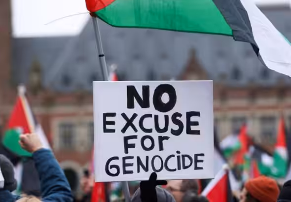 Pro-Palestinian protesters gather near the International Court of Justice (ICJ) carrying Palestinian flags and a poster reading “No Excuse for Genocide.” Photo: CBC.