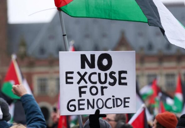 Pro-Palestinian protesters gather near the International Court of Justice (ICJ) carrying Palestinian flags and a poster reading “No Excuse for Genocide.” Photo: CBC.