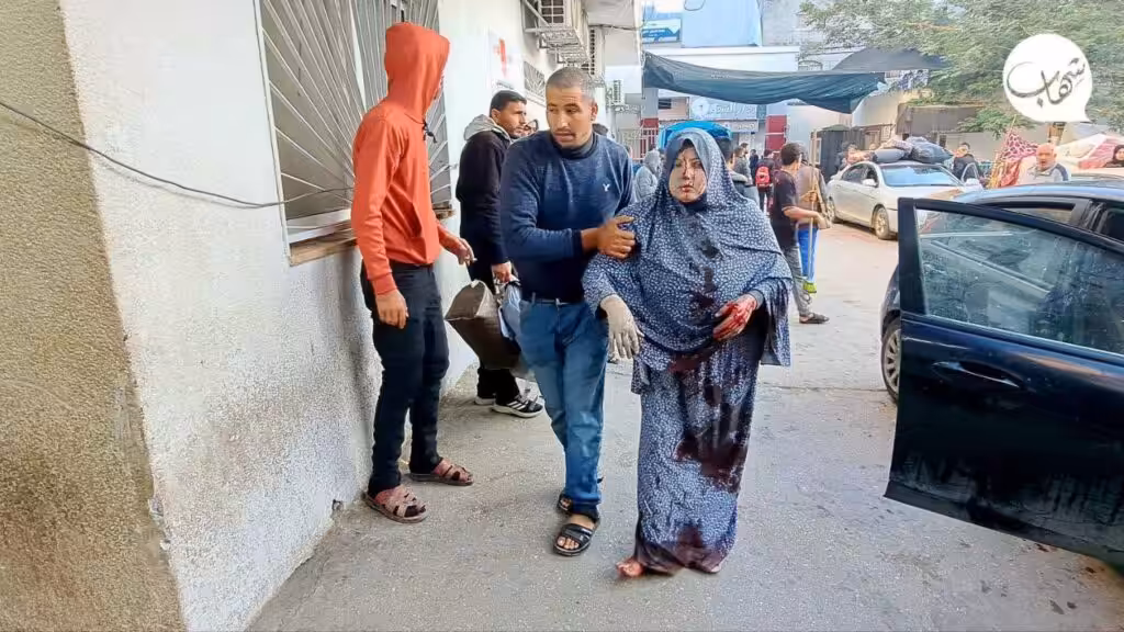 A woman injured in Israeli airstrike being escorted to the Kamal Adwan hospital, northern Gaza, December 2023. Photo: Social media.