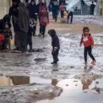 Children walk amongst puddles of water in the makeshift refugee camp in Rafah. Photo: AFP.