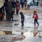 Children walk amongst puddles of water in the makeshift refugee camp in Rafah. Photo: AFP.