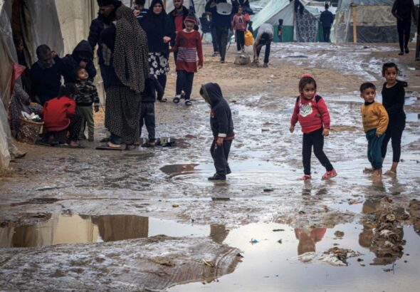 Children walk amongst puddles of water in the makeshift refugee camp in Rafah. Photo: AFP.