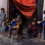 A Palestinian woman and her children cook food outside a house in Gaza, December 22, 2023. Photo: AFP.