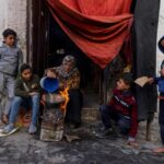 A Palestinian woman and her children cook food outside a house in Gaza, December 22, 2023. Photo: AFP.