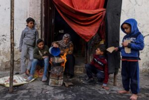 A Palestinian woman and her children cook food outside a house in Gaza, December 22, 2023. Photo: AFP.