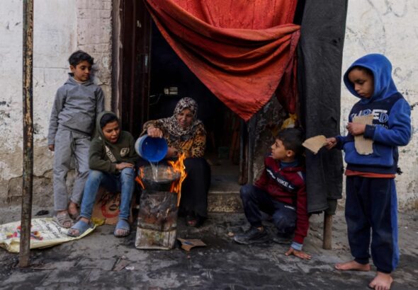 A Palestinian woman and her children cook food outside a house in Gaza, December 22, 2023. Photo: AFP.