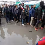 Palestinian refugees in line for food in the rain outside the shelter in Deir al-Balah. Photo: UNRWA.