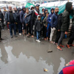 Palestinian refugees in line for food in the rain outside the shelter in Deir al-Balah. Photo: UNRWA.