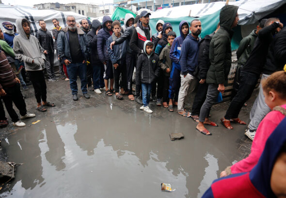 Palestinian refugees in line for food in the rain outside the shelter in Deir al-Balah. Photo: UNRWA.