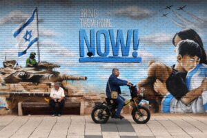Zionist mural in Occupied Palestine depicts Israeli occupation bombers and a tank and settlers hugging with the phrase "Bring them home NOW!" Nov. 23, 2023. Photo: Associated Press