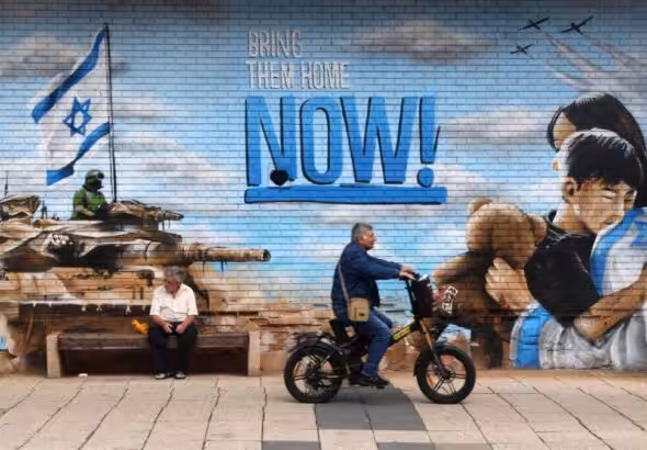 Zionist mural in Occupied Palestine depicts Israeli occupation bombers and a tank and settlers hugging with the phrase "Bring them home NOW!" Nov. 23, 2023. Photo: Associated Press