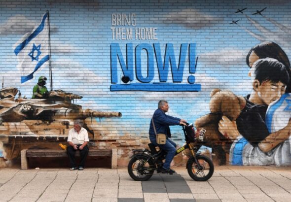 Zionist mural in Occupied Palestine depicts Israeli occupation bombers and a tank and settlers hugging with the phrase "Bring them home NOW!" Nov. 23, 2023. Photo: Associated Press