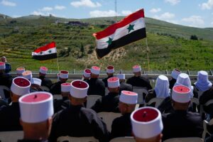 Druze men sit with Syrian flags during a rally marking Syria's Independence Day, in the Druze village of Majdal Shams in the Israeli-occupied Golan Heights, on the border with Syria, Monday, April 17, 2023. Photo: AP.