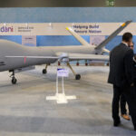 Delegates in front of Adani Defence and Aerospace's Hermes 900, left, and Sky Striker, center, drones on display at the Drone Festival - Bharat Drone Mahotsav 2022, at Pragati Maidan in New Delhi, India. Photo: Bloomberg.