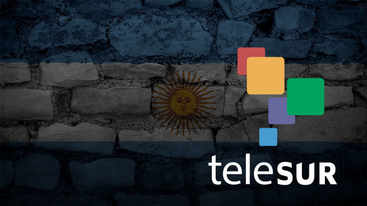 Photo composition showing the logo of Telesur over a transparent flag of Argentina on a wall of stone. Photo: Telesur/File photo.