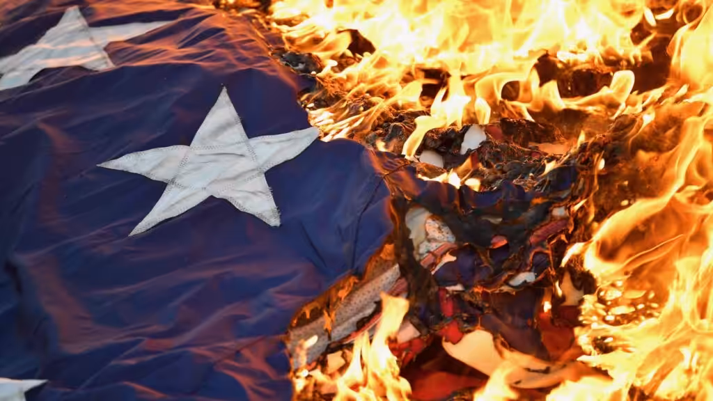 US flag on fire. Photo: Timothy D. Easley/Courier Journal.