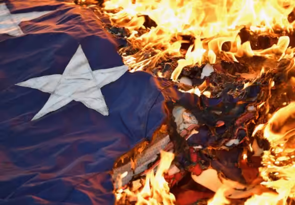 US flag on fire. Photo: Timothy D. Easley/Courier Journal.