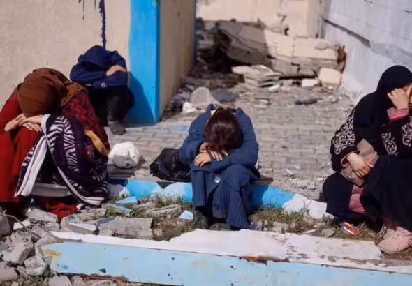 Palestinians rest next to damaged buildings after arriving in Rafah after they were evacuated from Nasser Hospital in Khan Younis in the southern Gaza Strip on February 4, 2024. Photo: Reuters.