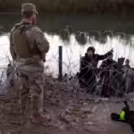 A migrant from Venezuela asks a Texas National guardsman directions to a processing center after crossing from Mexico into the United States on Dec. 17, 2023 in Eagle Pass, Tex. Photo: John Moore/Getty Images.